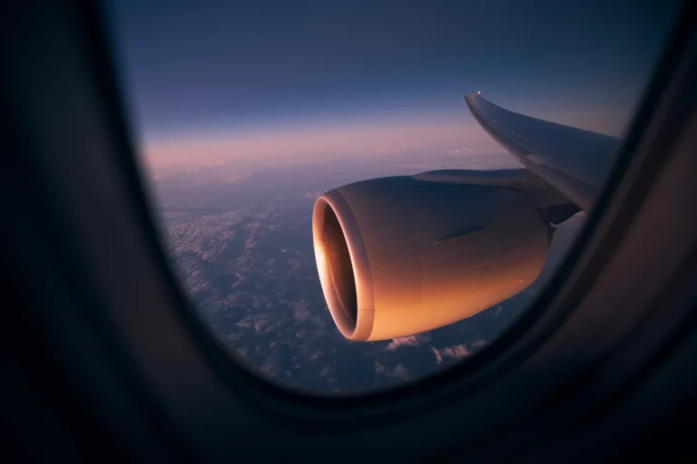 airplane wing and engine above clouds at sunset