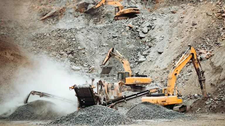 Heavy duty machinery working on quarry. Open pit ore mine with excavator and bulldozer and hydraulic crusher